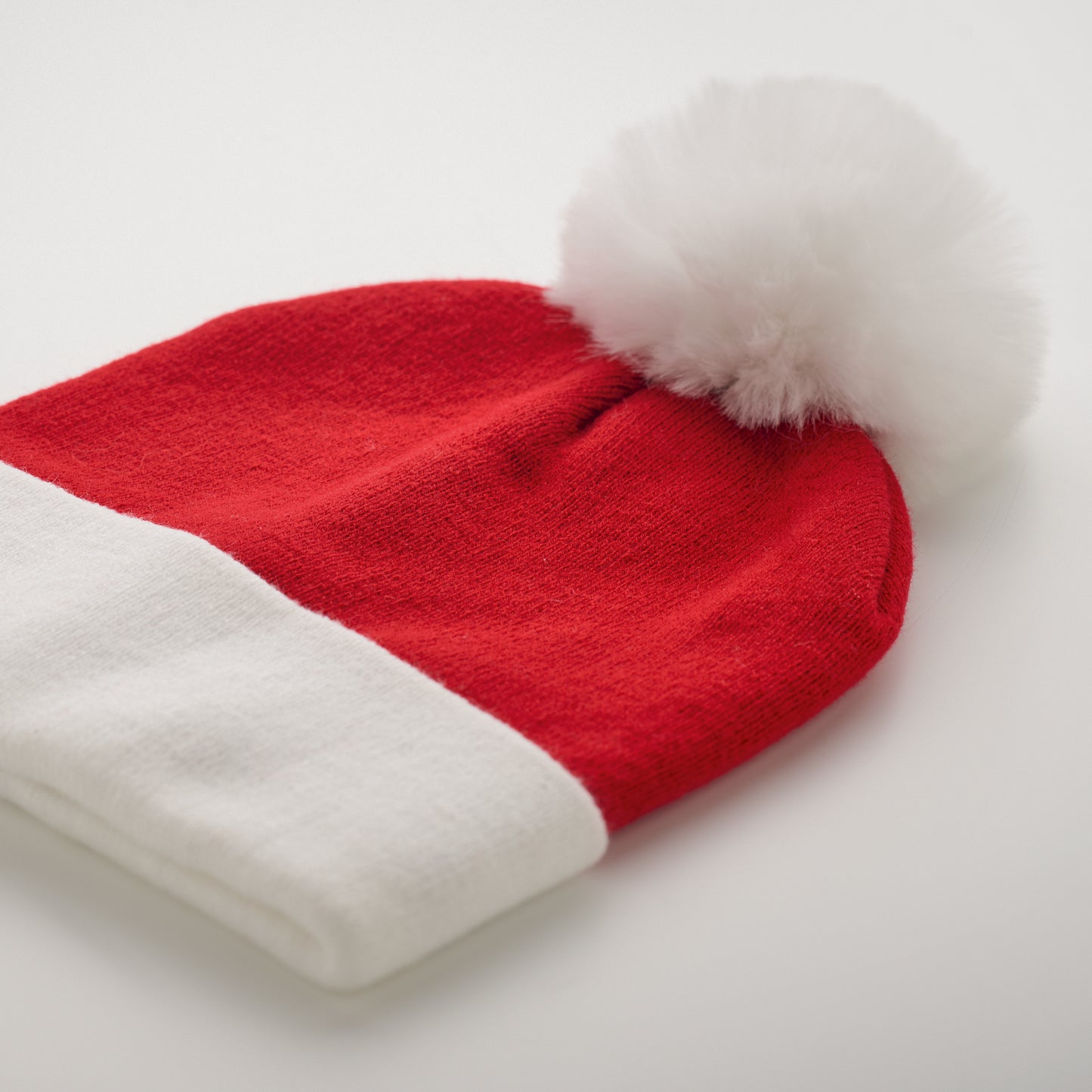 Weihnachtliche Strickmütze mit Bündchen und Bommel aus elastischem Acryl.