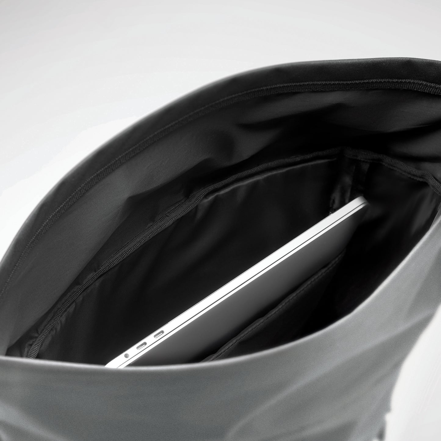 Rucksack mit Rollverschluss aus reflektierendem 190T-Polyester. Laptopfach Innenfach mit Klettverschluss seitliche Reißverschlusstasche.