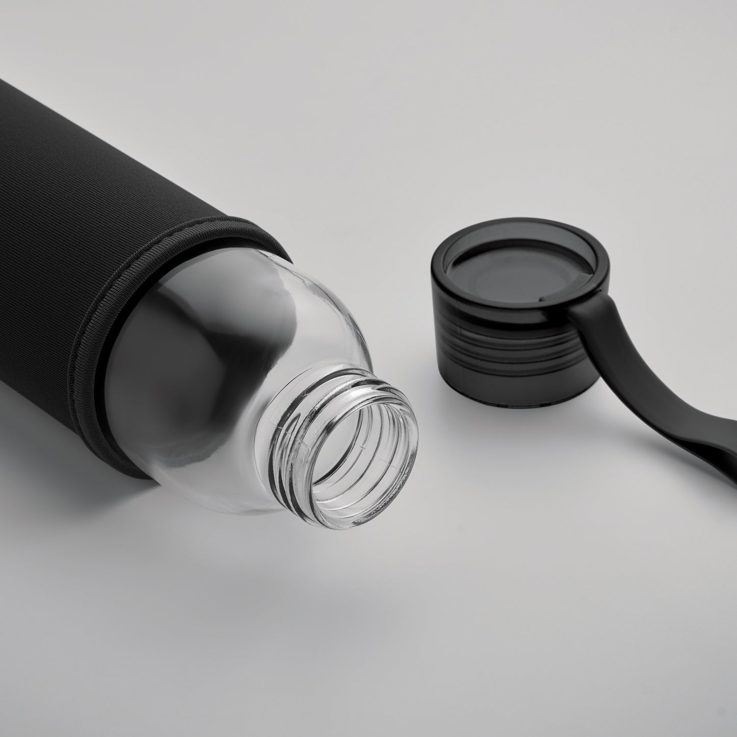 Trinkflasche aus recyceltem Glas mit Neopren-Schutzhülle und PP-Deckel mit Silikon-Schlaufe. Auslaufsicher. Füllmenge: