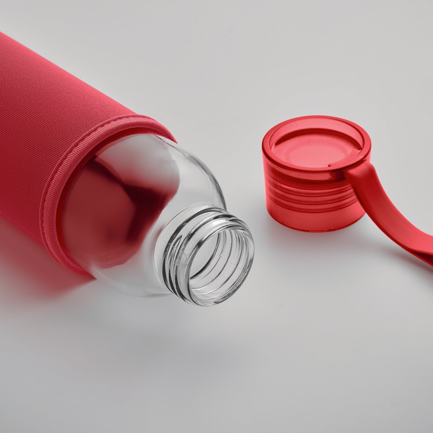 Trinkflasche aus recyceltem Glas mit Neopren-Schutzhülle und PP-Deckel mit Silikon-Schlaufe. Auslaufsicher. Füllmenge: