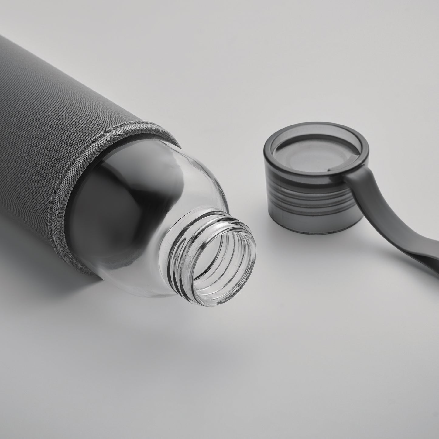 Trinkflasche aus recyceltem Glas mit Neopren-Schutzhülle und PP-Deckel mit Silikon-Schlaufe. Auslaufsicher. Füllmenge: