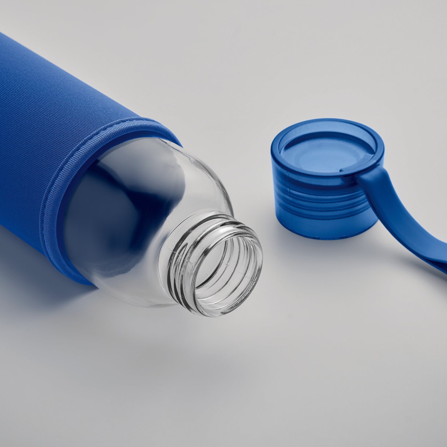 Trinkflasche aus recyceltem Glas mit Neopren-Schutzhülle und PP-Deckel mit Silikon-Schlaufe. Auslaufsicher. Füllmenge: