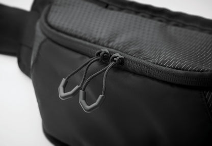 Gürteltasche aus wasserabweisendem 420D-Nylon mit 210D-Polyesterfutter. Reflektierender Streifen. Komplett gepolstertes Hauptfach. Große