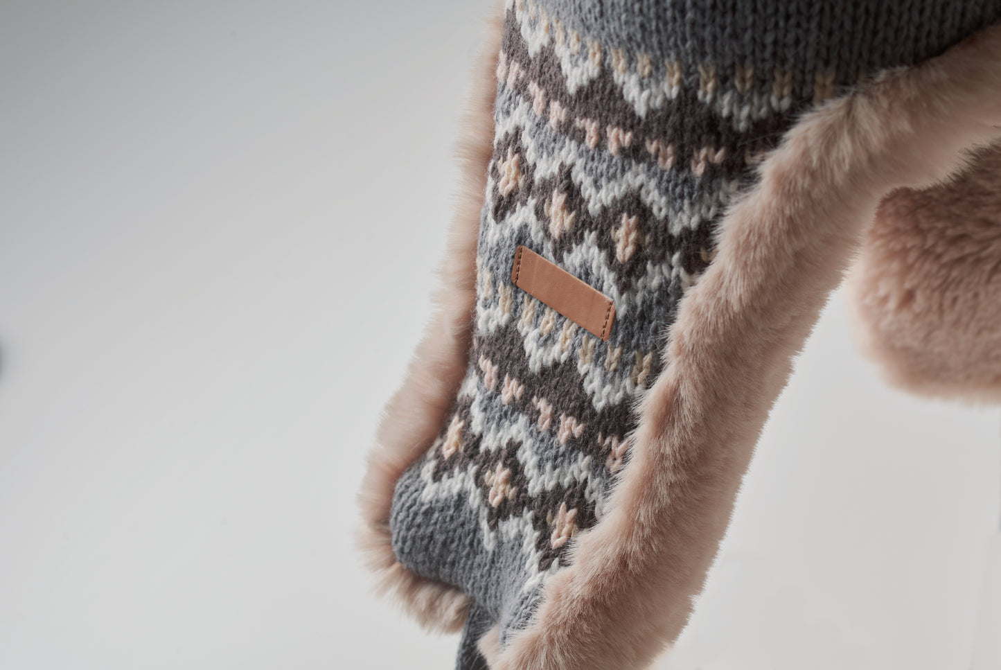 Gestrickte Mütze mit Ohrenklappen und Bommel aus Acrylfaser mit Polyester- und Fleece-Futter.