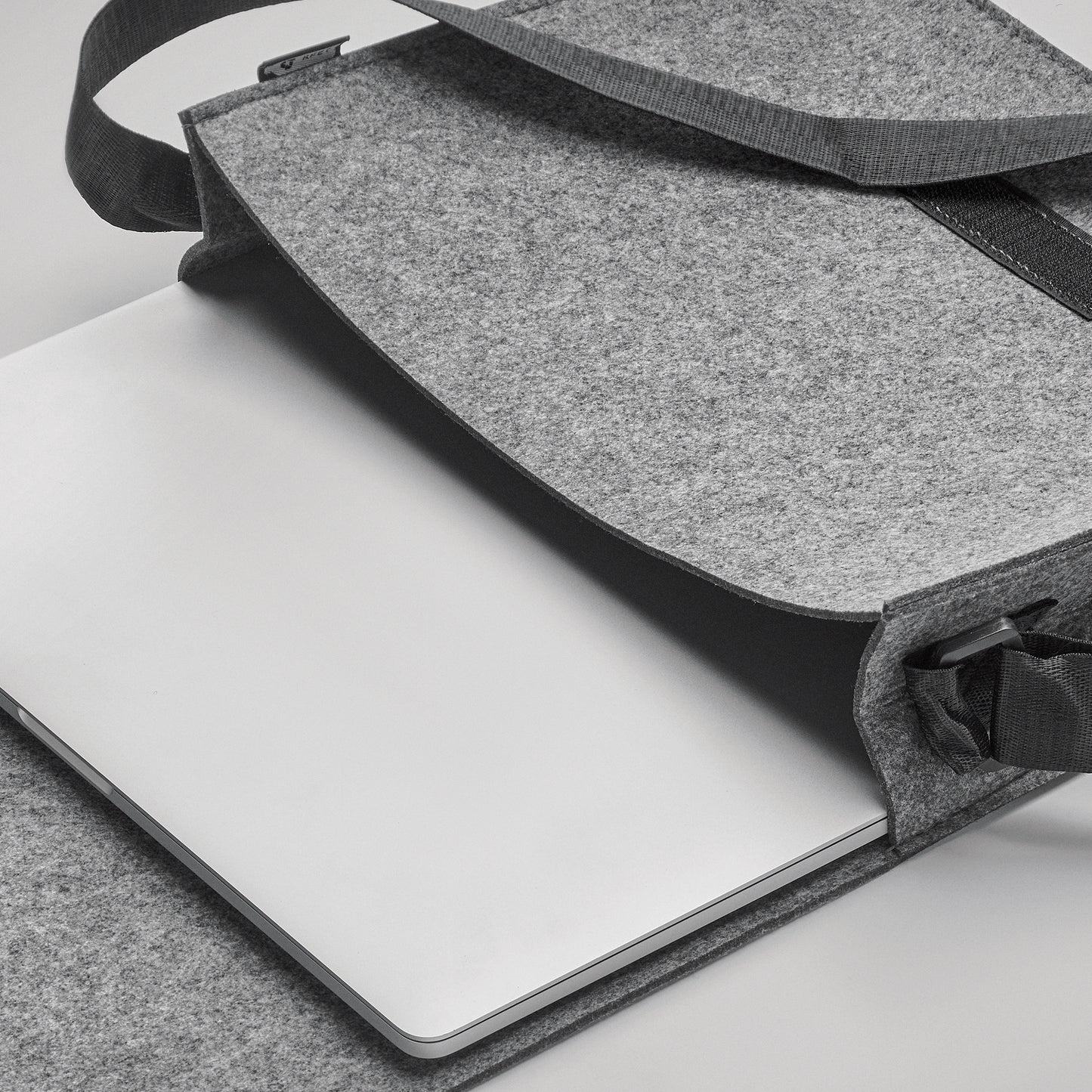 Umhängetasche aus RPET-Filz. Klettverschluss und Umhängegurt. Bietet Platz für einen 15'' Laptop.